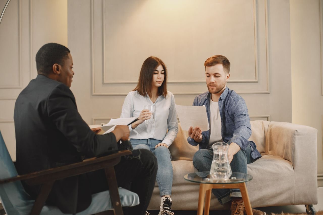Therapist counseling couple with documents in contemporary office setting.